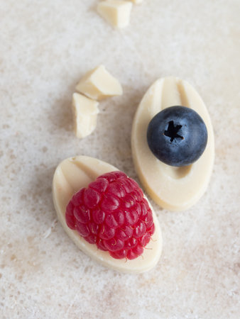 raspberry and blueberry on white chocolate top view close up