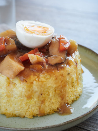close-up view of a millet cake with vegetable stew and poached egg halve on topの写真素材