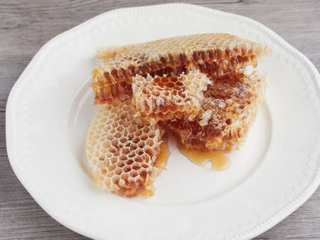 pieces of honeycomb full of raw organic golden honey on a white plateの写真素材