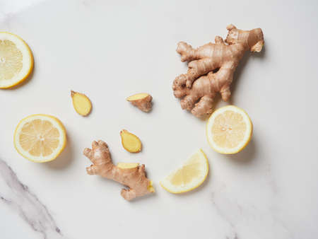 a piece of whole and sliced ginger root with lemon slices on the marble countertop. Antioxidant and healing healthy ingredients with vitamins. top viewの写真素材