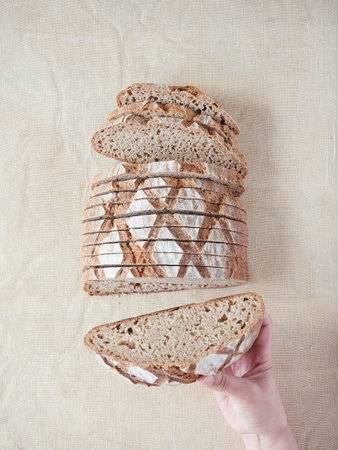 Hand holding a piece of artisan sourdough bread showing the well fermented honeycombed crumb inside....