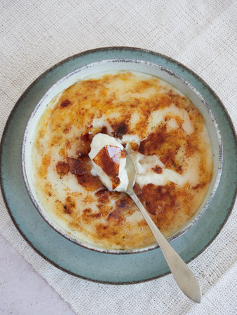 Top view of a spoonful of creamy rice pudding in the traditional Asturian style, served in a bowl with a delicious sweet caramelized sugar crust.の写真素材