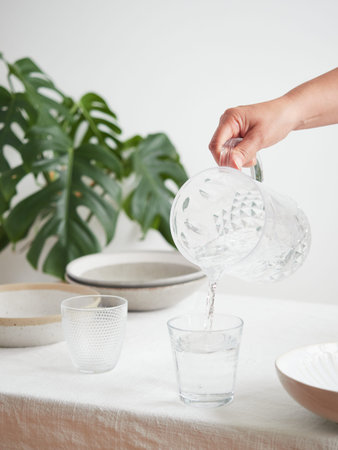 Concept of thirst and hydration. Drink water, healthy lifestyle. Woman's hand pouring fresh and pure...