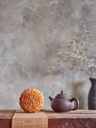 Composition of the Mid-Autumn festival. Front view of moon cake on bamboo mat next to small brown teapot on wooden table.の写真素材