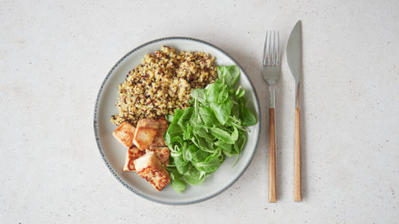 Appetizing plate of healthy food: quinoa, salad greens and roasted tuna. Top view on the countertop with cutlery, fork and knife.の写真素材
