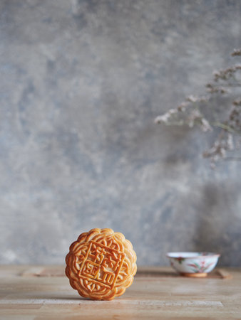 Front close-up of moon cake on wooden table. Chinese porcelain bowl in the background out of focus. Mid-autumn festival composition, gray background with copy space.の写真素材