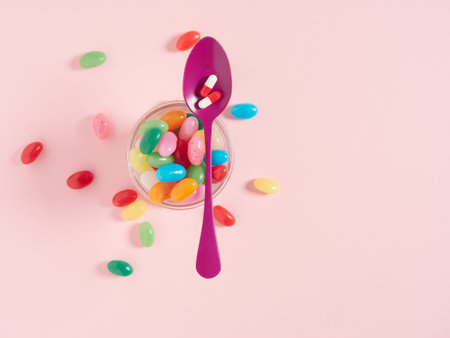 Concept of sugar addictive. Purple teaspoon with pills on a glass full of colored jelly beans.の写真素材