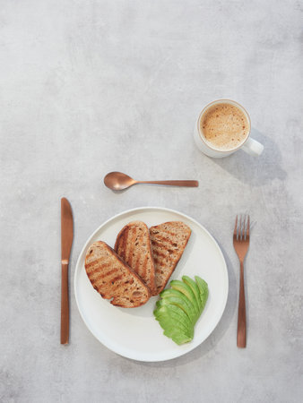 Healthy breakfast with toasted bread, avocado and coffee on light backgroundの写真素材