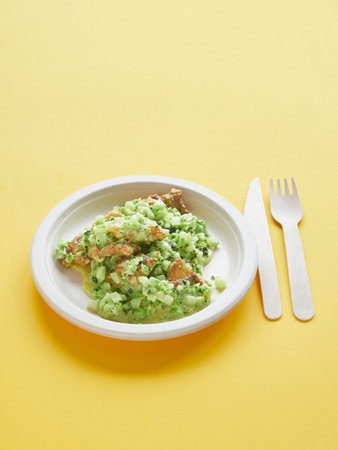 Healthy take-away meal: broccoli rice and chicken, on disposable ecological plate and wooden cutlery on yellow surface with copy space.の写真素材
