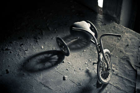 Old dusty tricycle standing on the wooden floorの写真素材