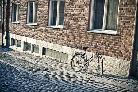 Bicycle standing near the brick wall on the sidewalkの写真素材
