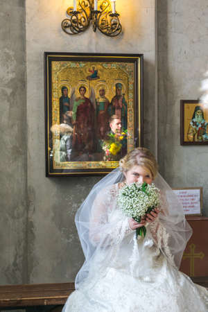 MOSCOW - MARCH 10: bride sits and and smells flowers during orthodox wedding ceremony on March 10, 2013 in Moscowのeditorial素材