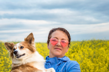 woman in pink glasses is holding a white-red dog in her arms. concept happy pensionの写真素材