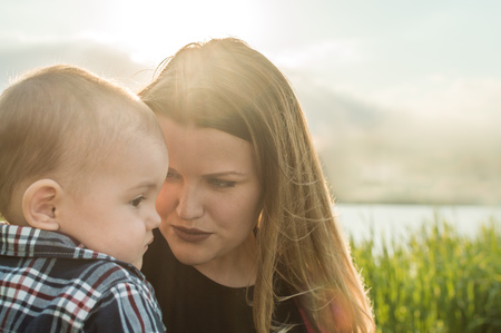 close-up portrait of woman and mother on a background of lake and grass in the sun. concept mother and sonの写真素材