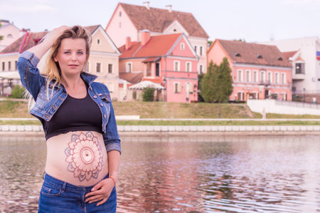 Pregnant woman with a picture on her stomach in the city. concept body artの写真素材