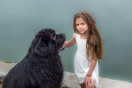 little girl and newfoundland on a blue lake backgroundの写真素材