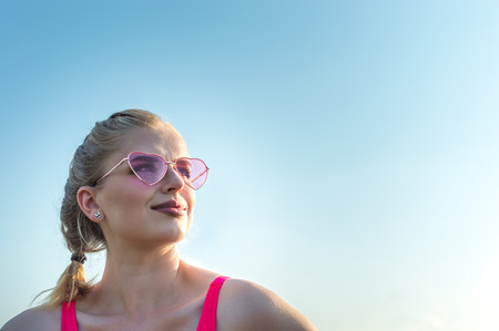 portrait of a young woman in pink sunglasses against the blue sky. Concept happinessの写真素材