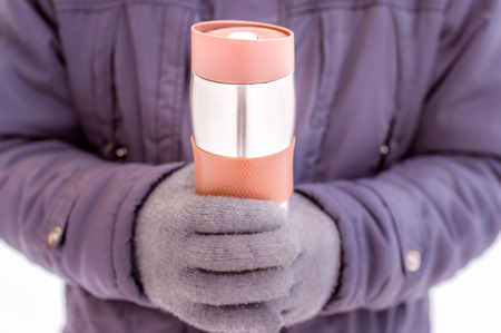 flask in the hands of a man close-up against the snowの写真素材