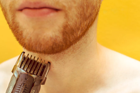 Close-up of a man shaving his beard with shaving machine
