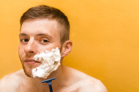 Young guy is shaving with a blade. Concept care for yourself.