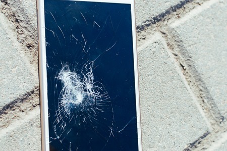 Broken smartphone on the asphalt close up. Glass replacement.の写真素材