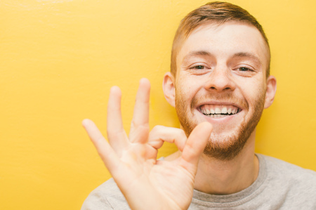 Young man shows ok gesture with his fingers with a smileの写真素材