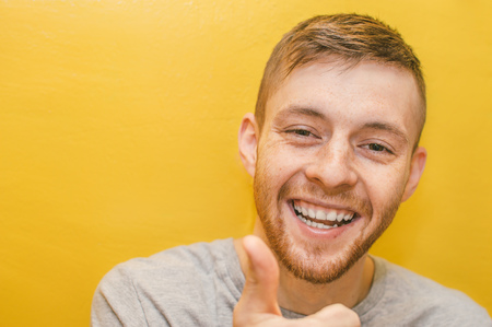 Young man shows gesture of super fingers with a smile on his faceの写真素材