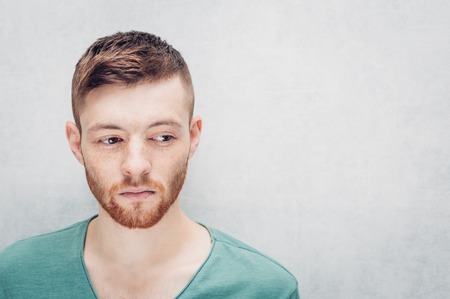 Sad young man on a gray background. Closeup portrait.の写真素材