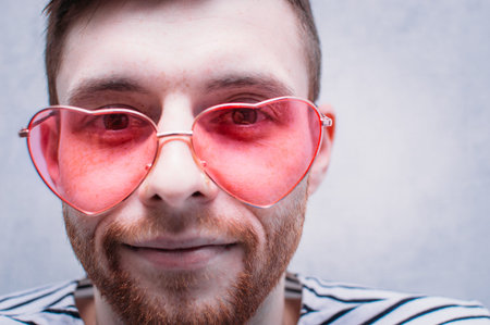 Face of a young man in pink glasses close-up. Valentine's Day.