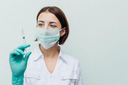 Young female doctor holds a syringe in her hand and looks at it. Concept diseaseの写真素材
