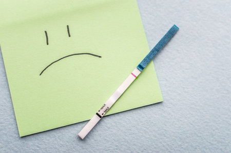One-strip pregnancy test and sad smile. Infertility concept