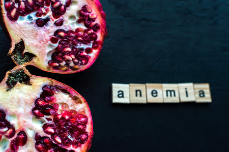 Cut pomegranate on a black background. Concept anemiaの写真素材