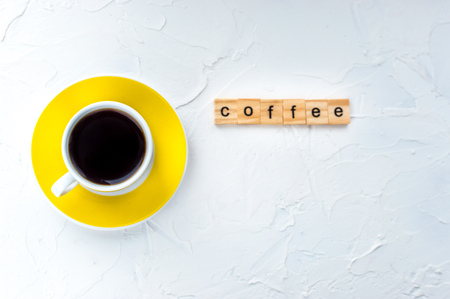 Yellow cup of coffee on a white background. Minimalism. Top view. Horizontal photoの写真素材