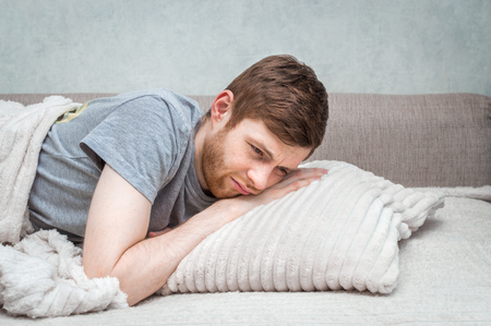 Portrait of a man on the bed. Concept insomnia. The man did not sleep and does not want to get out of bedの写真素材