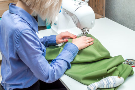 Seamstress sews clothes on a sewing machine. Close-up. Concept sewing workshop.Tailoring Process