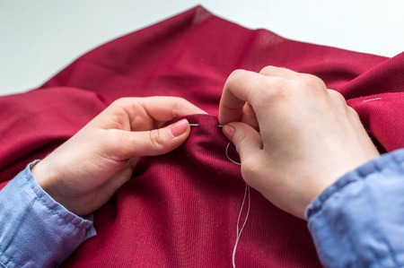 Seamstress sews clothes by hand. Woman's hands close up.の写真素材
