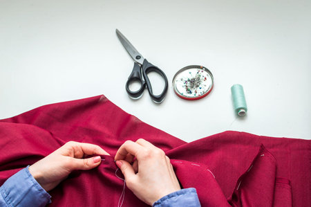 Seamstress sews clothes by hand. Woman's hands. Close-up. Handcraft concept.
