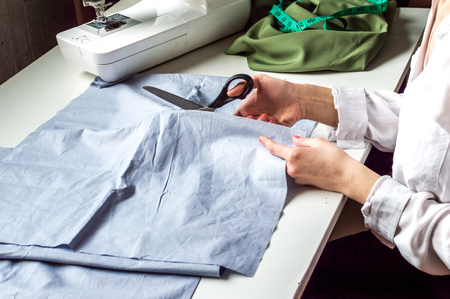 seamstress makes cutting fabric on the desktop. Studio tailoring. Clothing production, sewing processの写真素材