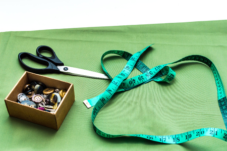 Accessories for sewing. tailor concept. Multicolored fabrics, tape measure, scissors and buttons closeup.の写真素材