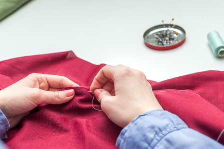 Seamstress sews clothes by hand. Woman's hands. Close-up. Handcraft concept.の写真素材