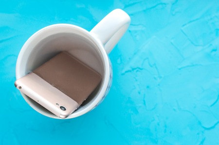 Concept digital detox. Smartphone in a mug with waterの写真素材