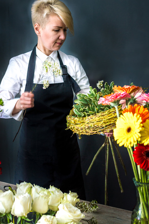 Woman florist at flower shop preparing a bouquet of flowers. Copy space. Vertical photoの写真素材