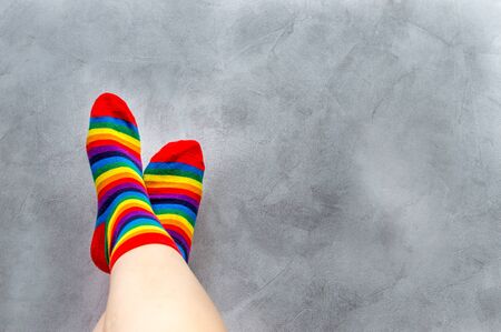 On a gray background, close-up of the feet of a man in multi-colored socks. Rainbow. Symbol. Concept LGBTの写真素材