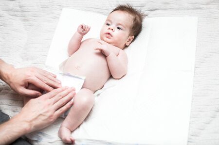 young dad puts a fresh diaper on his baby. Close-up. Newborn care concept. Dad does hygiene to his babyの写真素材