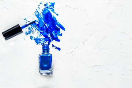 Bottle of blue nail polish on a white background. Classic Blue color 2020. Stains of varnish. Sprayの写真素材