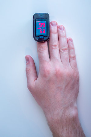 pulse oximeter is placed on the index finger of a man's hand to measure saturation. Close-up.