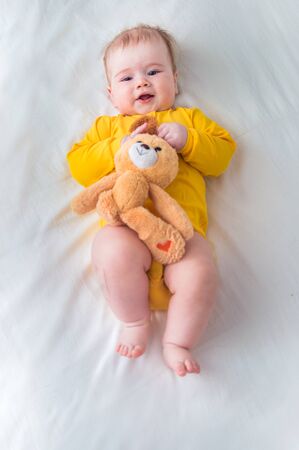Portrait of a happy smiling infant in bed with a toy in his hand. Vertical photoの写真素材