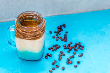 dalgona coffee with coffee beans on a wooden background close upの写真素材