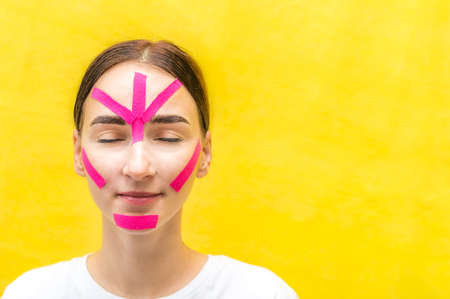 Portrait of a young woman with kinesio tapes on her faceの写真素材