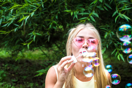 Young woman blows soap bubbles in the street. Close-up portrait. Happiness and positive emotions...